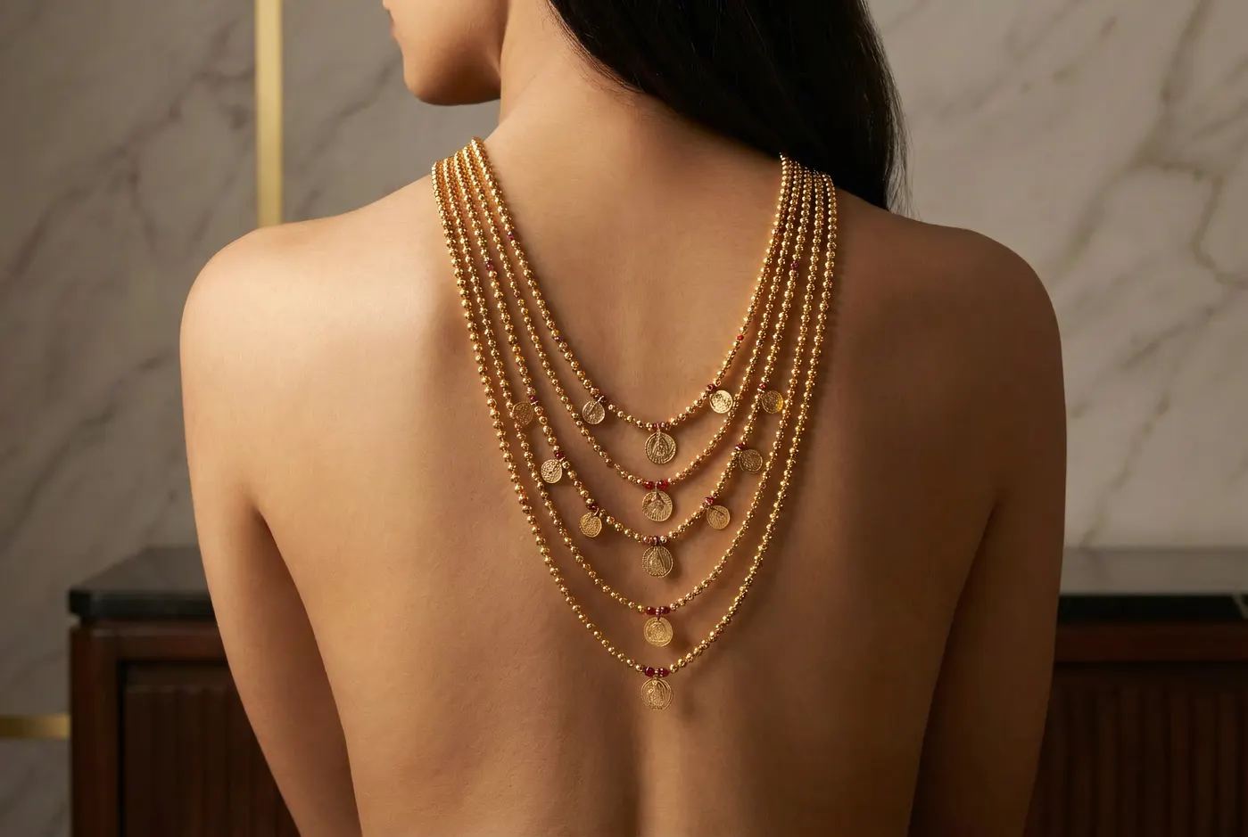 Multi-strand Kasu Mala coin necklace draped on back, editorial